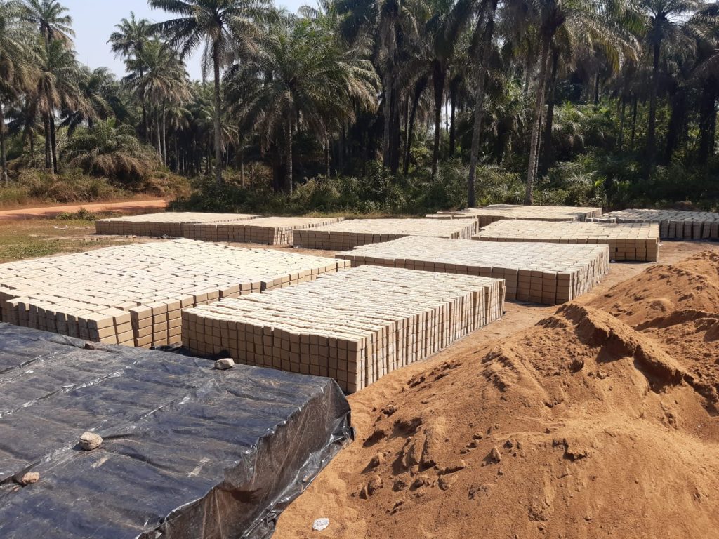 Blick auf das Steinlager für unsere neue Schule in Barbara, Sierra Leone. Insgesamt neun große Haufen voller fertig produzierter Steine, die in der Sonne aushärten sind zu sehen.